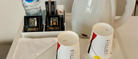 A tray with a Nestlé Pure Life water bottle, two coffee cups, a tea set, and a white electric kettle.