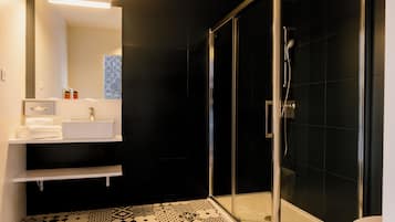 Une salle de bain moderne avec une douche à parois de verre, un lavabo blanc et un carrelage décoratif.