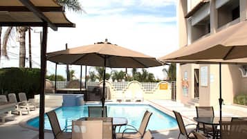 Una piscina al aire libre, sombrillas, sillones reclinables de piscina