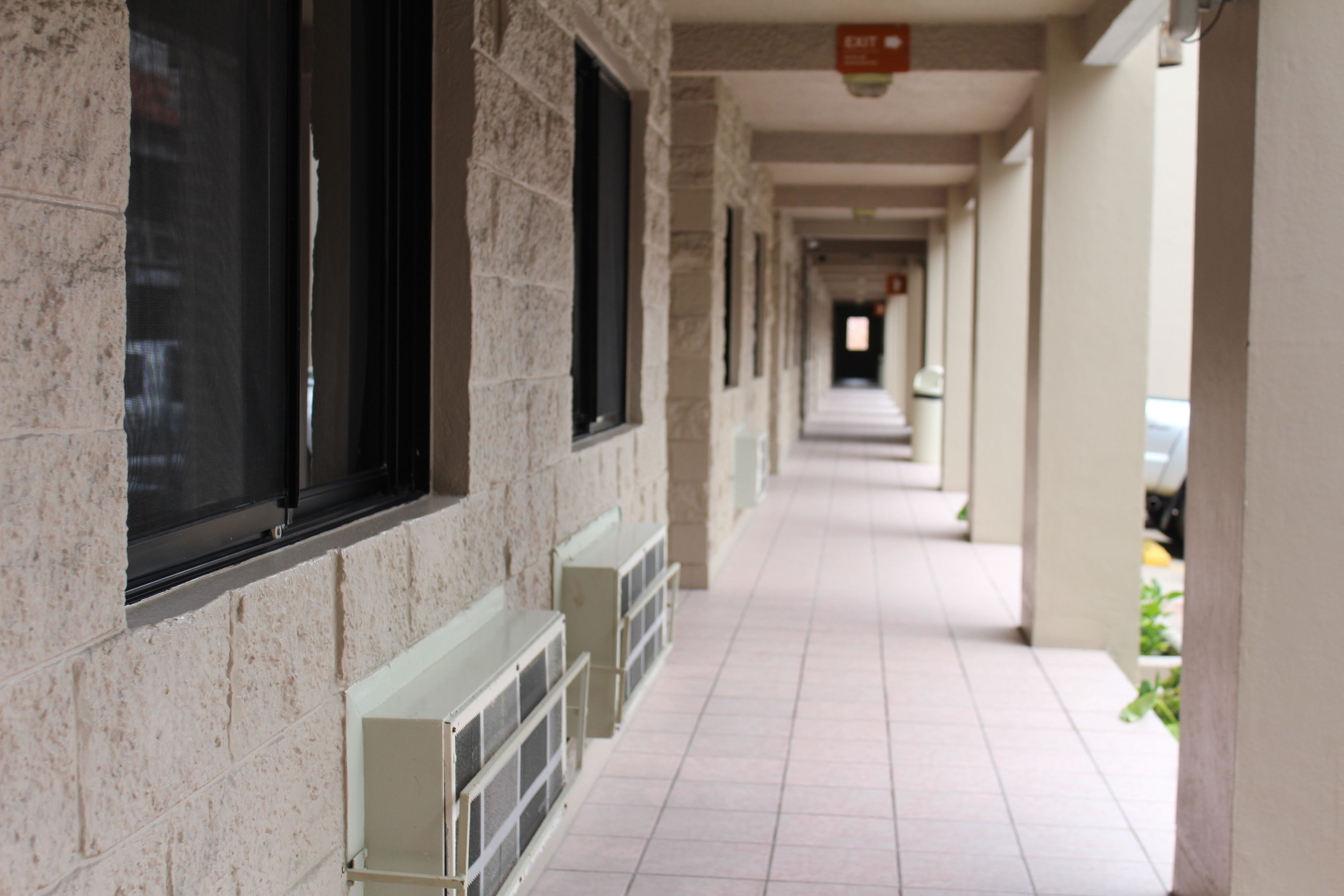 A corridor with stone walls, windows, and a tiled floor.