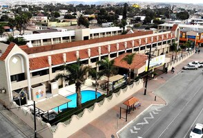 A hotel with a swimming pool, multiple floors, and a street view.