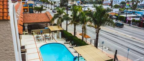 Un hotel con piscina, mobiliario exterior y vistas a la ciudad.