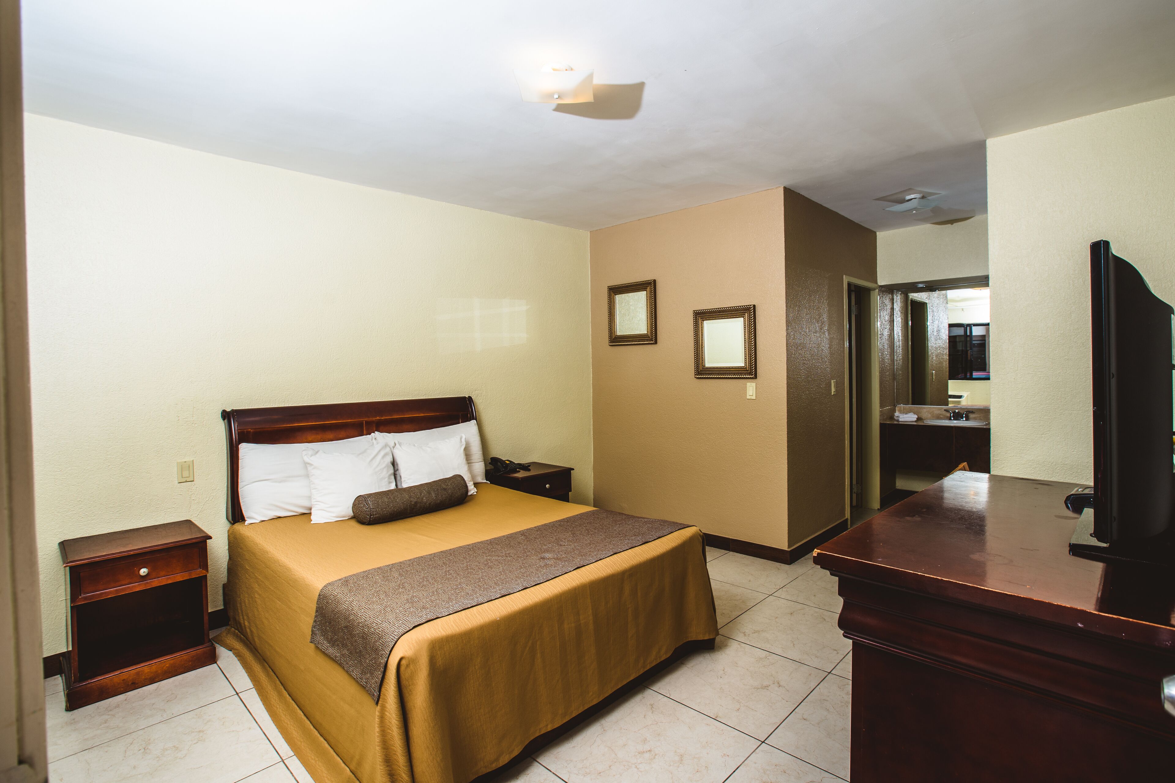 Una habitación de hotel con cama, mesita de noche, cómoda y espejo.