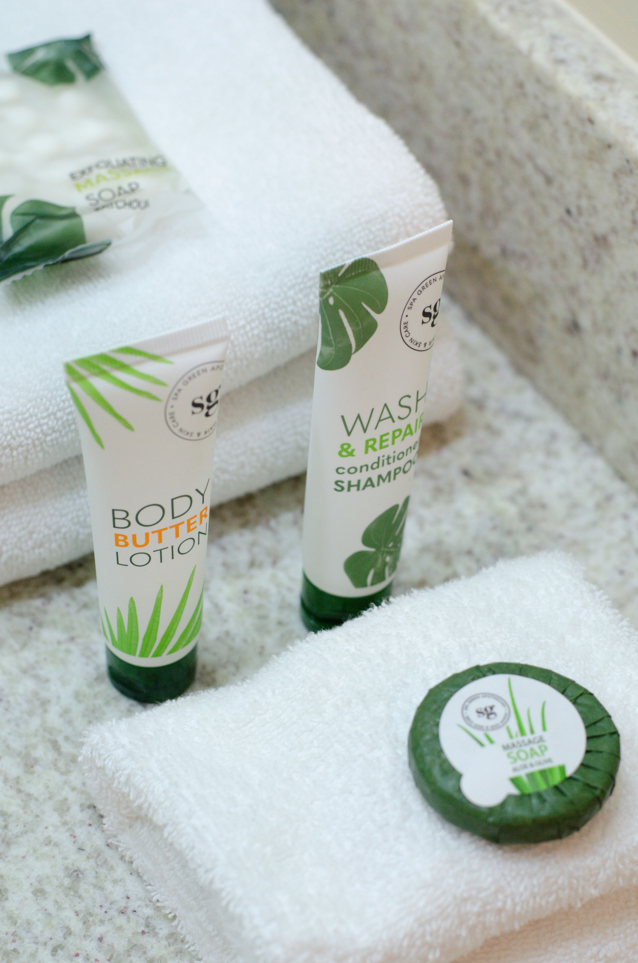 Un baño con una toalla blanca, crema exfoliante y una botella de champú.
