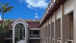 Un immeuble à plusieurs étages doté d’une cour intérieure, de balcons et d’un toit recouvert de tuiles.