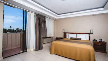 Una habitación de hotel con una cama grande, una mesita de noche, una ventana con cortinas y vistas al exterior.