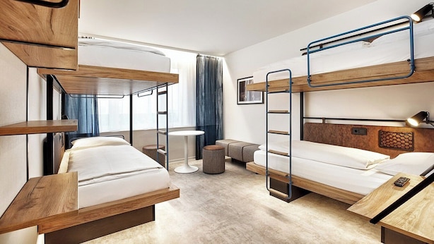 Una habitación de hotel con literas, una mesita redonda pequeña y un sofá.