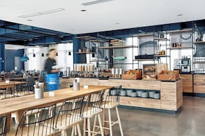 Una cocina moderna con una isla central, taburetes de bar y una persona al fondo.