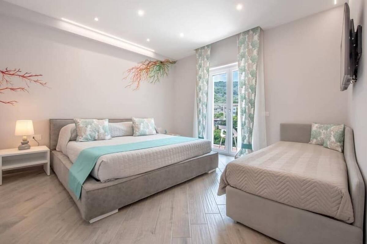 Ein Schlafzimmer mit Bett, Nachttisch und Blick ins Freie.