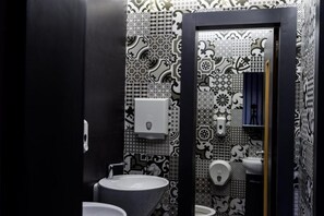 A bathroom with patterned tiles, a sink, a toilet, and a hand dryer. - Hotel Vitality Terminus (Kenitra)