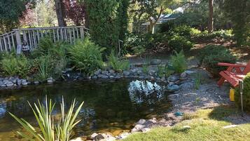 A garden with a pond, a wooden fence, and a red chair.