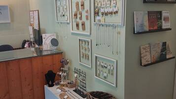 Una joyería con varios escaparates llenos de collares y pendientes. También hay estanterías con libros y un mostrador de madera con una caja registradora.