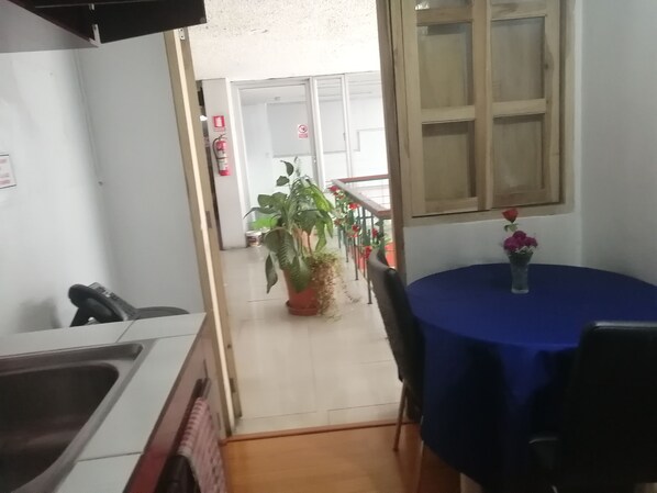 Una cocina con un lavabo y un comedor con mantel azul y un florero con flores.