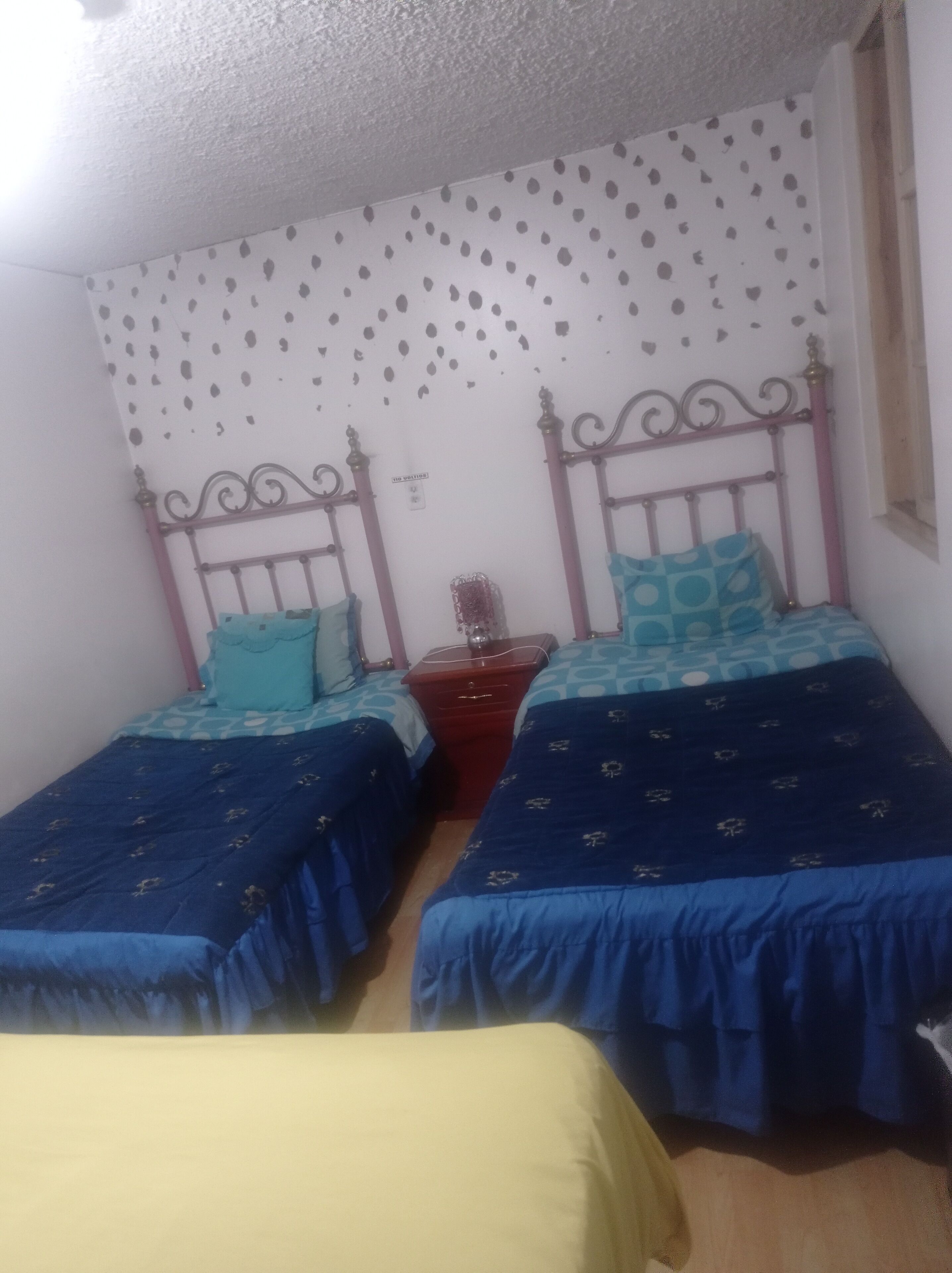 Un dormitorio con dos camas individuales, una mesita de noche y un aparador.