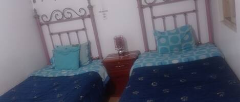 Un dormitorio con dos camas individuales, una mesita de noche y un aparador.