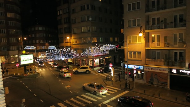 Veduta notturna di una strada con edifici, auto e lampioni.