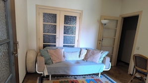Una camera accogliente con un letto, un tappeto colorato, una finestra con un pannello decorativo e una sedia.