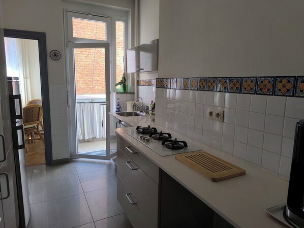 A modern kitchen with a gas stove, sink, and white tiled backsplash.