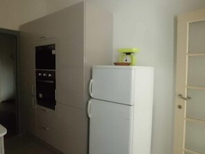 Compact kitchenette with refrigerator, oven, and microwave.