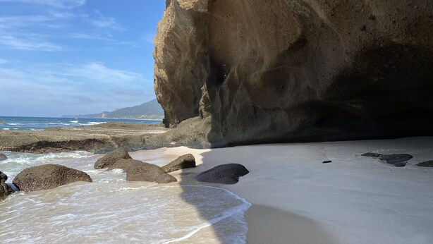 Una playa con rocas grandes y olas.