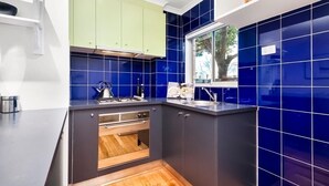 Eine kleine Küche mit Backofen, Gasherd und einem Fenster über der Spüle.