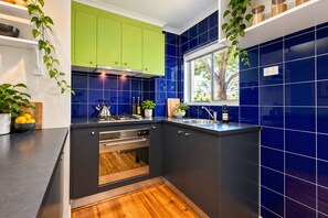 Een moderne keuken met donkere kastjes, een rvs afzuigkap en een raam dat voor natuurlijk licht zorgt.
