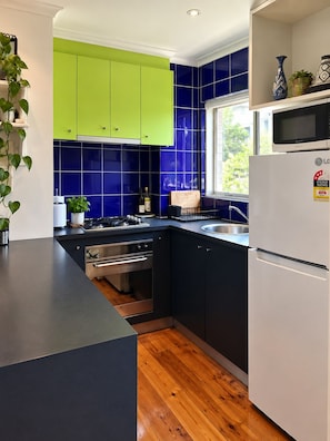 Une cuisine moderne avec des meubles de couleur verte, un four à micro-ondes et un évier.