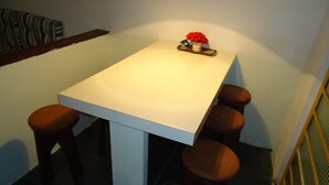 Un pequeño comedor con una mesa blanca y cuatro taburetes de madera.