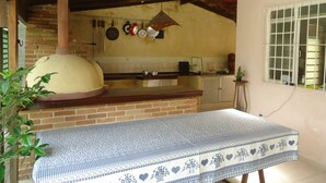 Una cocina con horno de ladrillo, ollas colgantes y una ventana con barrotes.