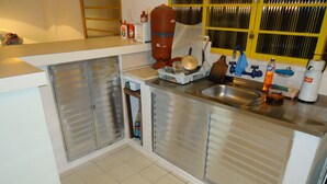 Una cocina con armarios de acero inoxidable, un fregadero y diversos utensilios.