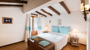 A bedroom with a wooden bed, a nightstand, a lamp, and a window with curtains. - Monte Argentario, Tuscany, whole villa with panoramic view. (Monte Argentario)