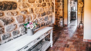 A stone wall with a white console table and a vase of flowers. - gite / house ardéchoise of character with swimming pool (Labatie-D'andaure)