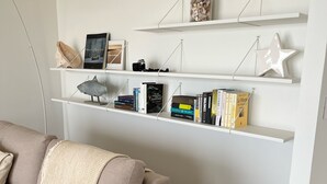 A living room with a beige sofa, a coffee table with decorative items, and white shelves with books and decorative objects. - Breathtaking sea view  (Quiberon)