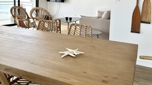 A modern living room with a wooden dining table, wicker chairs, a sofa, and a painting on the wall. - Breathtaking sea view  (Quiberon)