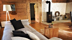 Una sala de estar acogedora con un sofá, una lámpara, una chimenea y una pared de madera rústica.