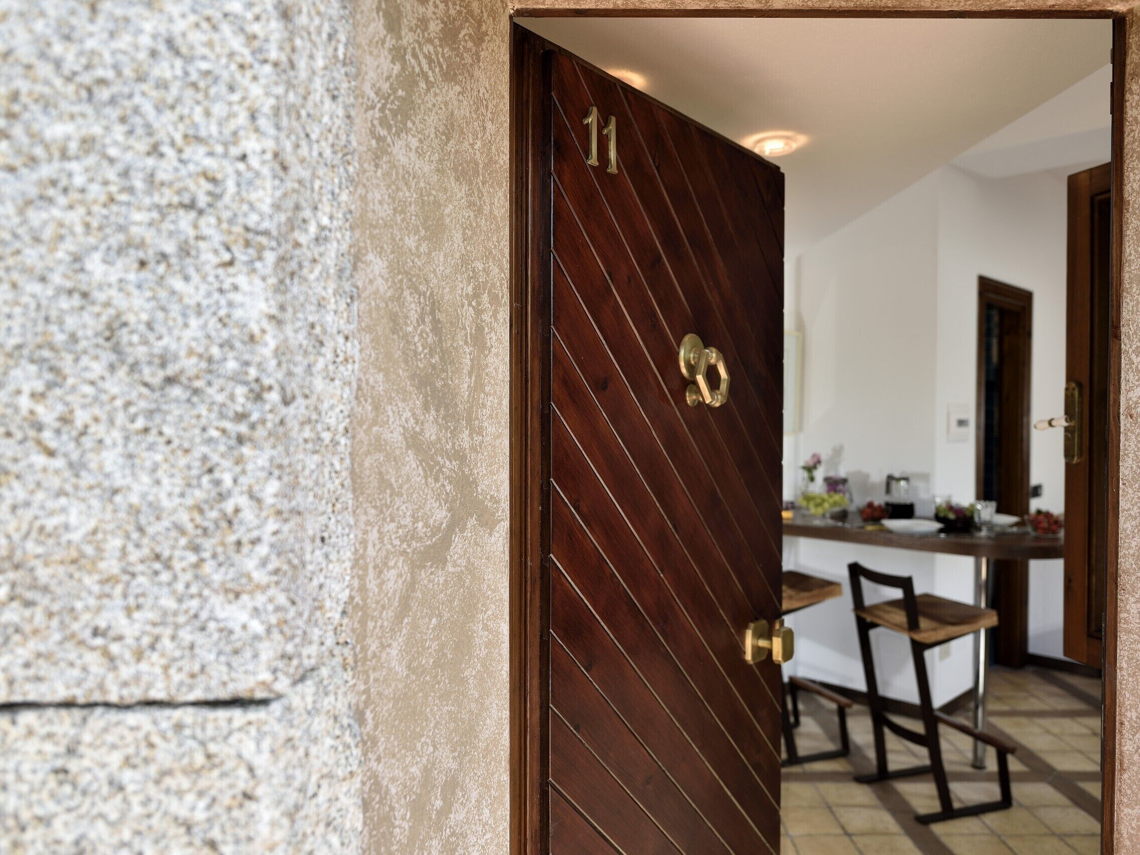 A wooden door with the number 11, leading into a room with a kitchen area visible.