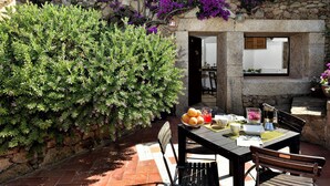 A stone building with a patio area featuring a table with chairs, a basket of fruit, and a coffee maker. - Holiday apartments L'Ea di Lavru 
Studio apartment TOP INTERIOR DESIGN (Porto San Paolo)