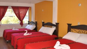A hotel room with four single beds, each with a red bedspread and white pillows, and a decorative swan on each bed. - Hotel El Portal Sololateco (Sololá)