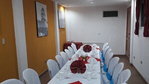 A conference room with a long table set for a meeting, white chairs, and red tablecloths. - Hotel El Portal Sololateco (Sololá)