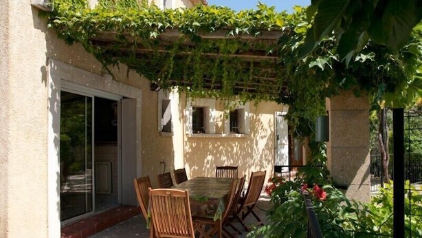 An outdoor patio with a table and chairs, surrounded by a pergola covered in greenery. - Spacious, pleasant house in the heart of a Provencal village (Le Pin)