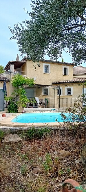 Een tweelaags huis met een zwembad, balkon en tuin.