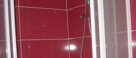 A shower enclosure with red tiles and a white frame.