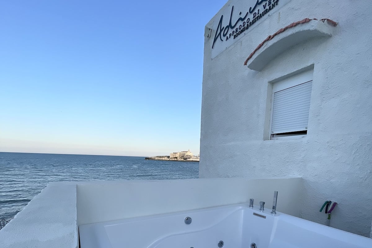 Un bâtiment blanc avec une enseigne indiquant « Adli Diveners » et une grande baignoire installée à l’extérieur.