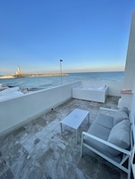 Una terrazza sul tetto con vista sul mare e un faro.