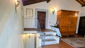 A staircase with a metal railing leading to a wooden door, a wall-mounted light fixture, and a large wooden cabinet. - House / Villa - Quarrata with private pool (Quarrata)