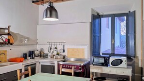 A rustic kitchen with a wooden ceiling, a hanging light fixture, a window with blue shutters, and a table with chairs. - House / Villa - Quarrata with private pool (Quarrata)