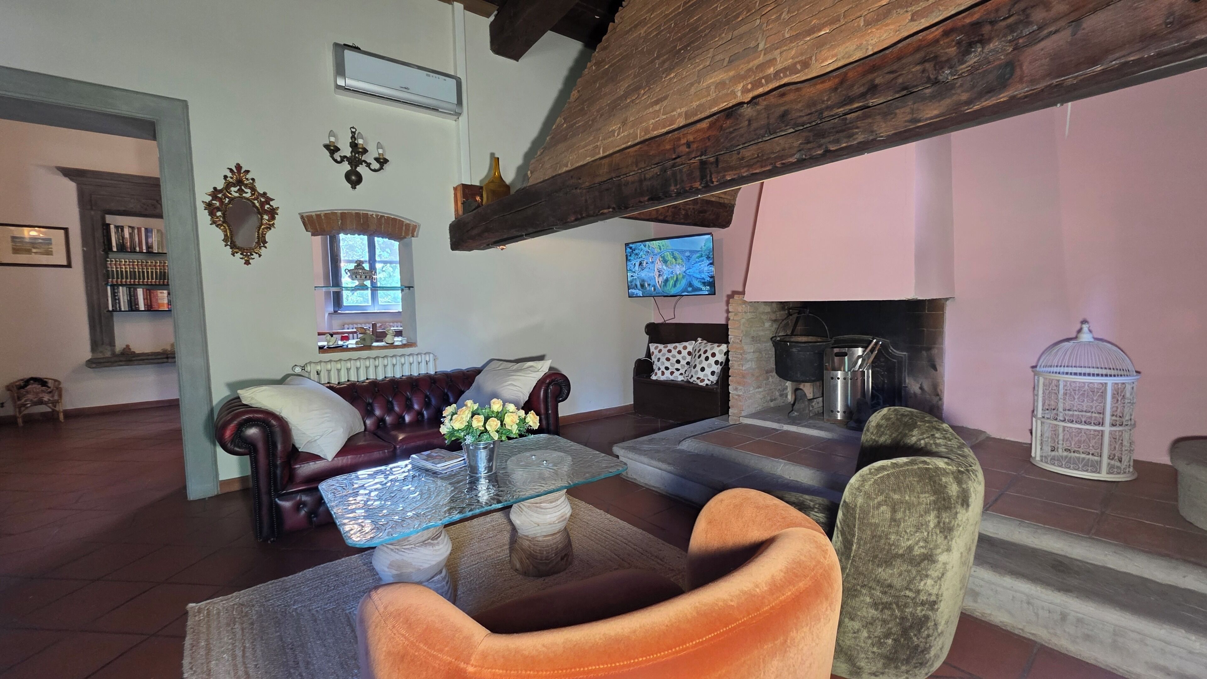 A living room with a fireplace, a television, a bookshelf, and a coffee table with flowers.