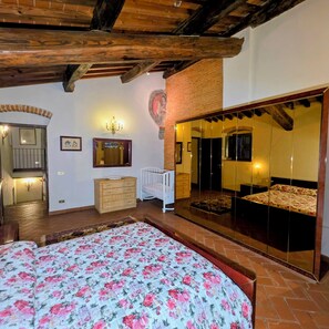 A bedroom with a large bed, a wooden ceiling, a mirror, a dresser, and a crib. - House / Villa - Quarrata with private pool (Quarrata)