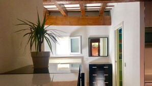 Une pièce avec un plafond en bois, une plante en pot, un miroir et un meuble noir.