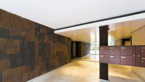 Un hall spacieux avec un mur en pierre, un meuble en bois et un plafond doté d’un éclairage linéaire.